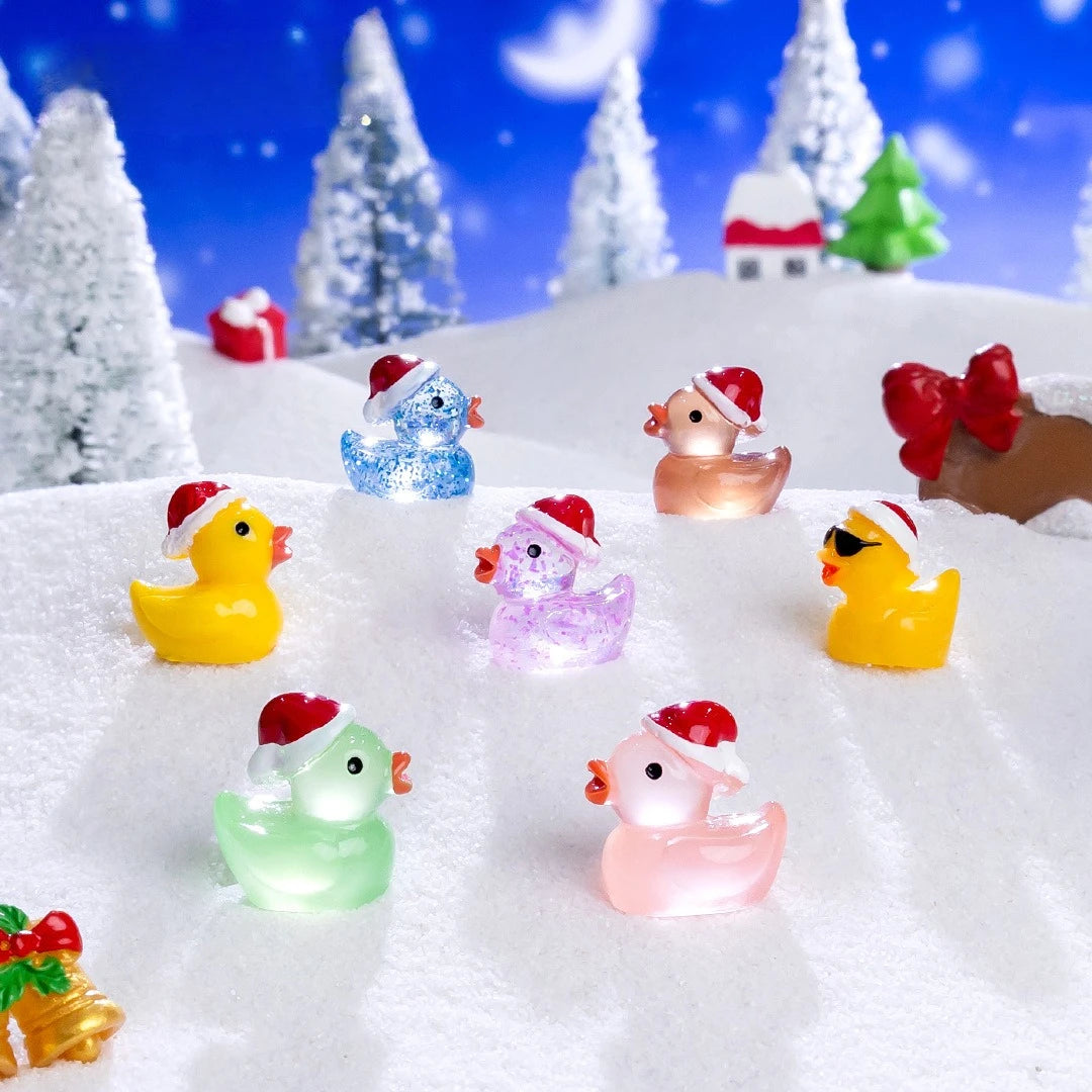 A collection of glow-in-the-dark Christmas duck figurines wearing Santa hats scattered on a snowy surface.