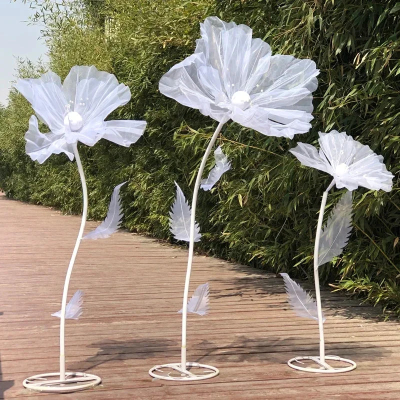 Three white mesh flowers on slender stems with delicate white wings used as wedding decoration