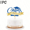 A white cake decorated with gold accents and a blue glitter topper that reads Congrats Graduates