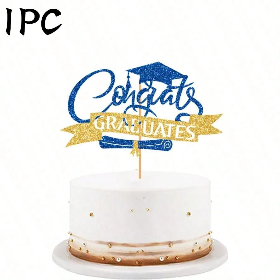 A white cake decorated with gold accents and a blue glitter topper that reads Congrats Graduates
