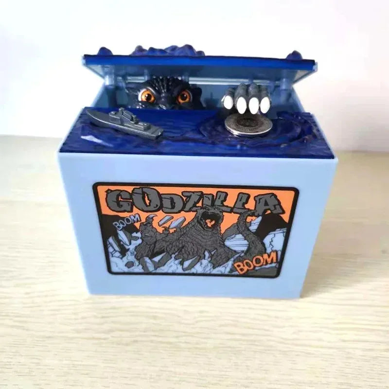 A blue resin piggy bank shaped like Godzilla featuring a small figure and an eye detail.