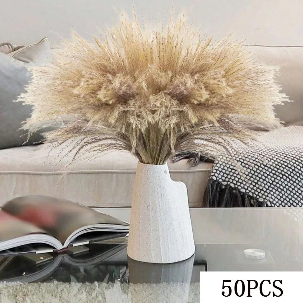 A dried pampas grass bouquet in a white ceramic vase displayed on a glass table.