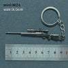 A miniature alloy gun model keychain with a silver finish is shown next to a ruler.