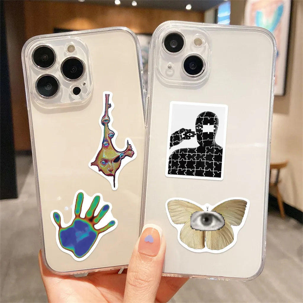 A hand holds a clear phone case featuring black and white graffiti stickers on a light beige background.