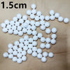 A collection of white polystyrene foam balls arranged in various shapes and clusters on a light surface.