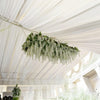 A cascading garland of white silk wisteria vines hanging from a white draped ceiling.