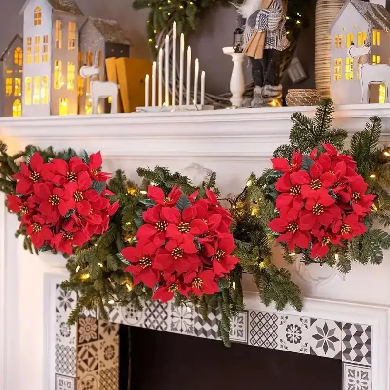 A festive arrangement of realistic artificial poinsettia flowers in red and green foliage displayed on a white mantelpiece.