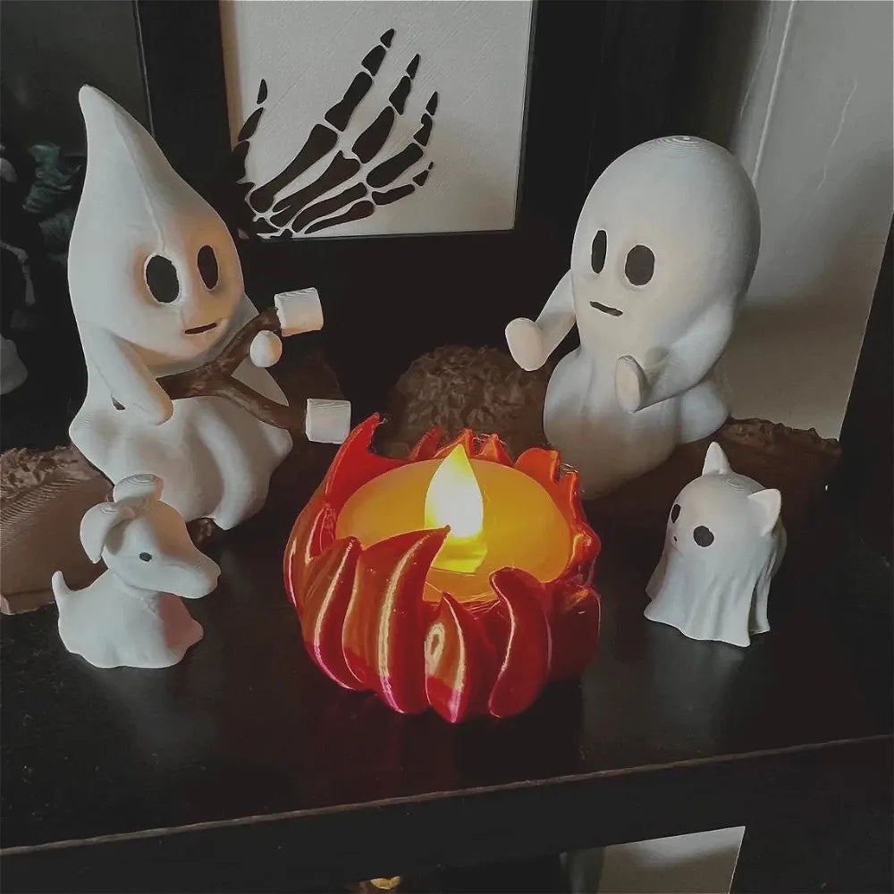 A set of white ghost figures and a red candle arranged on a dark surface for Halloween decor.