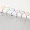 A row of colorful heavy duty purse and bag hooks in pastel shades pink, mint green, and lavender mounted on a white surface.