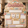 A personalized wooden sign for a child's first day of school featuring illustrations like a school bus, crayons, and various 
