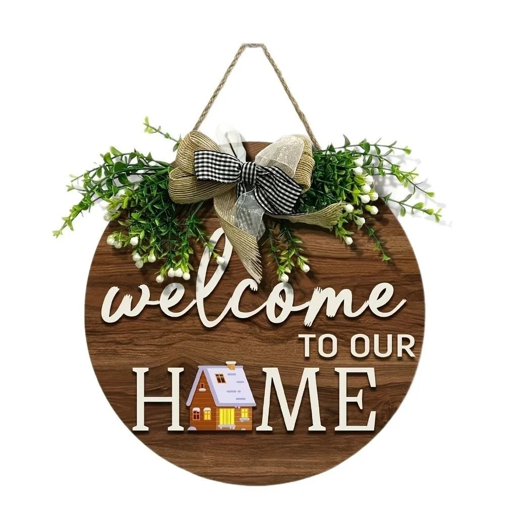 A round wooden welcome sign decorated with greenery and a bow, featuring the text Welcome to Our Home.