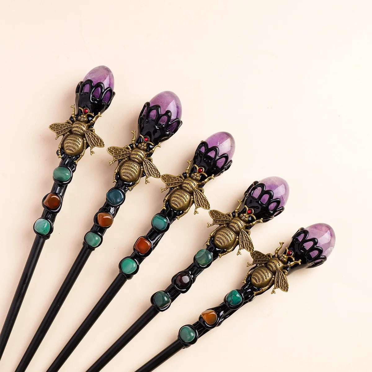A set of five amethyst bee crystal scepters with gold accents and green beads.