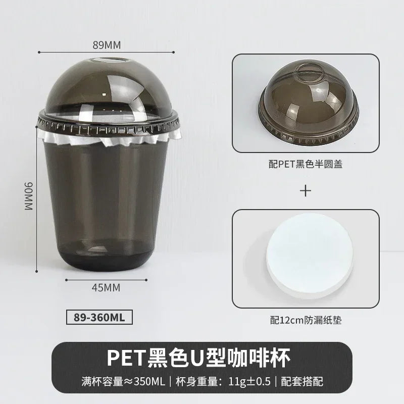 A black disposable U-shaped PET coffee cup with a clear lid and a white disc.