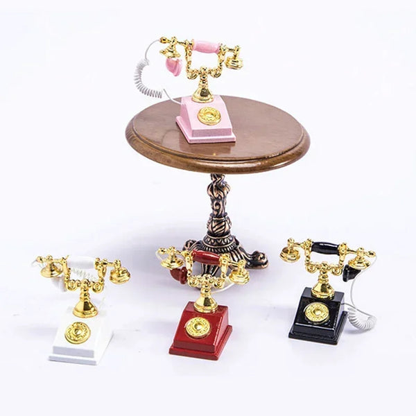 A vintage rotary desk phone miniature decor with gold and pink accents displayed on a wooden stand.