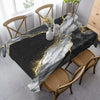 Mantel rectangular de mármol negro y dorado sobre una mesa de comedor de madera con sillas.