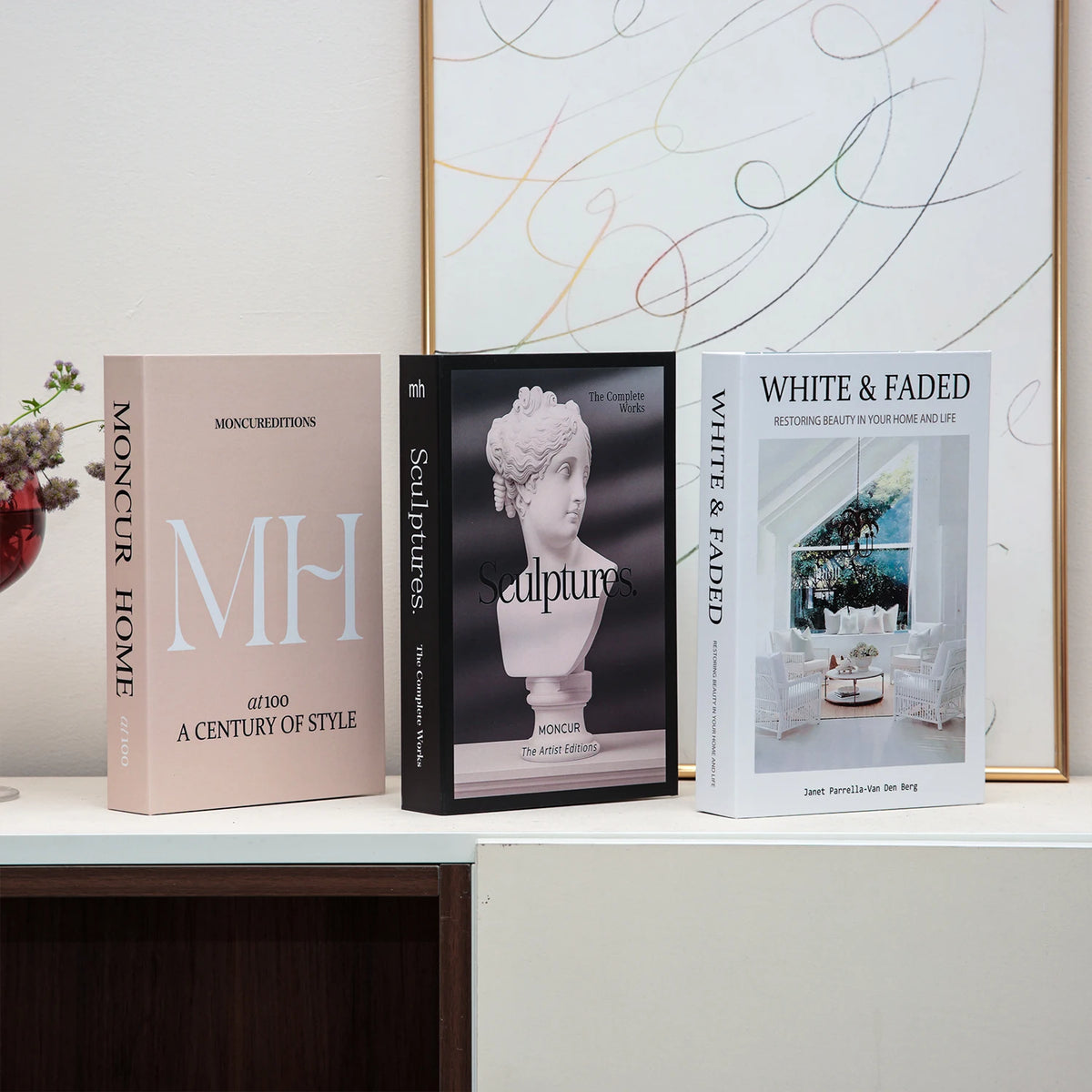 A set of three hardcover books featuring elegant typography and illustrations on a white shelf.