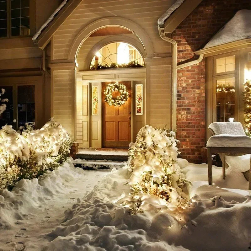 Outdoor garden décor featuring a brick facade and arched entryway decorated with warm fairy lights amidst snow.