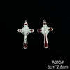 A pair of silver crucifix pendants featuring a figure of Christ and red enamel finish.