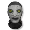 A grayscale mask resembling a face with cracked skin and glowing yellow eyes, worn as carnival headgear.