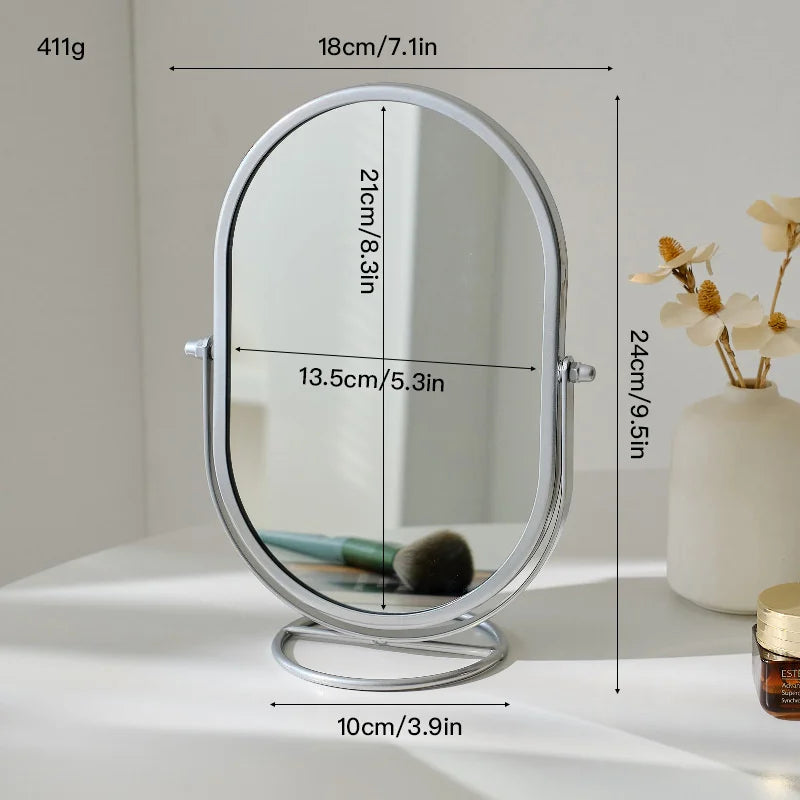 A silver oval vanity mirror with a rotating feature is shown on a white surface.
