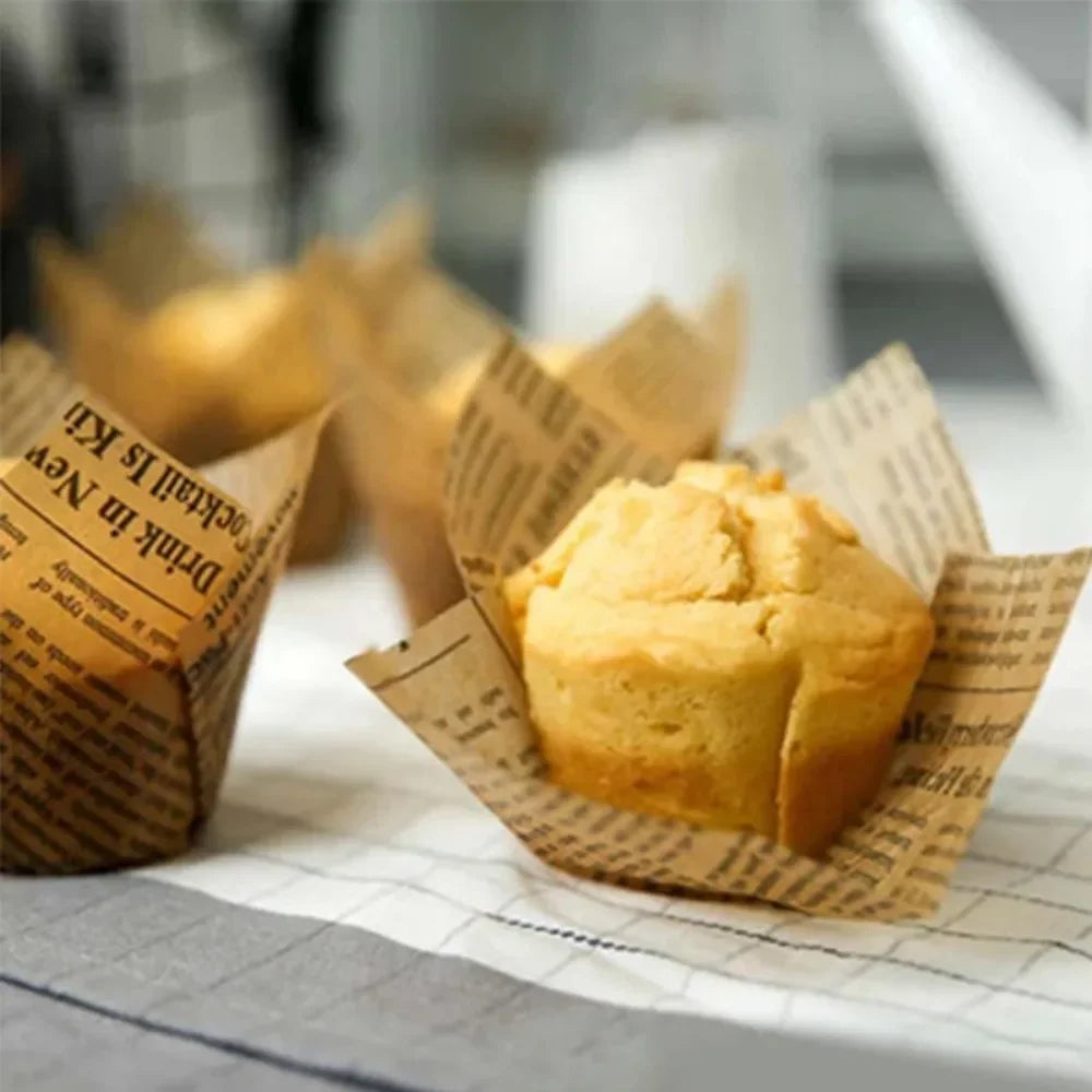 A golden cupcake is shown in a newspaper style liner on a white surface.