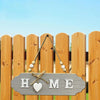 A wooden welcome sign with the word HOME carved into it, hanging on a rustic fence.