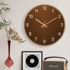 Minimalistische Holz-Wanduhr mit Roségold-Akzenten, hängend über ein gerahmtes Record und Gitarrencase.