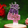 Glitter number 4 birthday candle with rhinestone crown cake topper on a wooden slice.