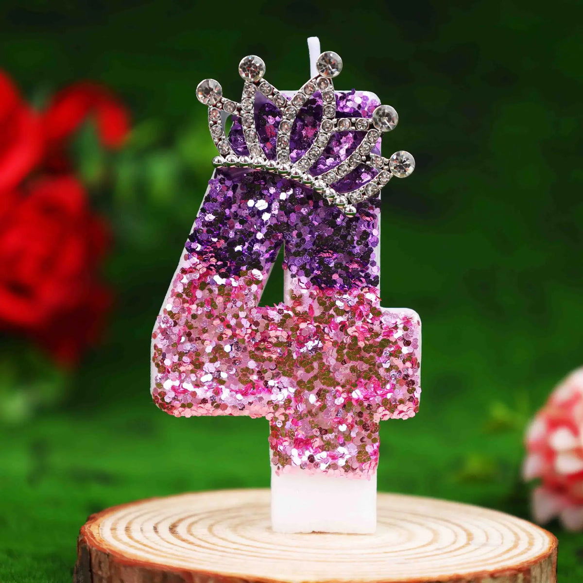 Glitter number 4 birthday candle with rhinestone crown cake topper on a wooden slice.