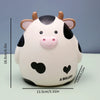 A cute white and black cow figurine shaped like a piggy bank for saving money.