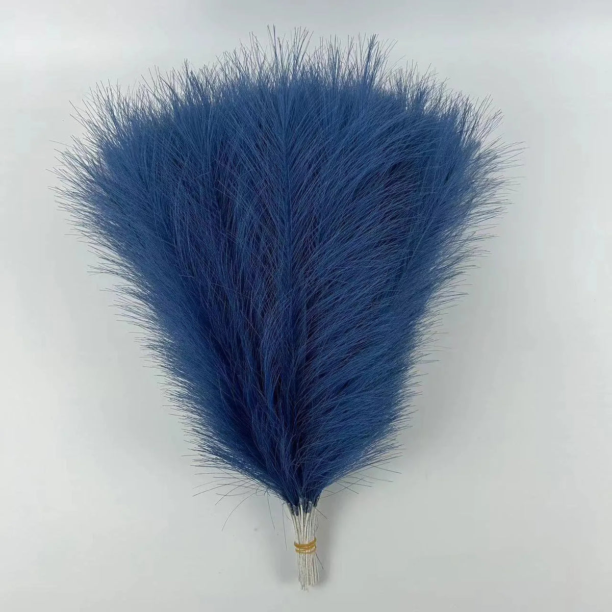 A fluffy, deep blue artificial pampas grass bouquet used for boho home decor.