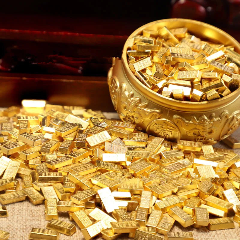 A pile of small gold bar pattern decor pieces next to a golden bowl.