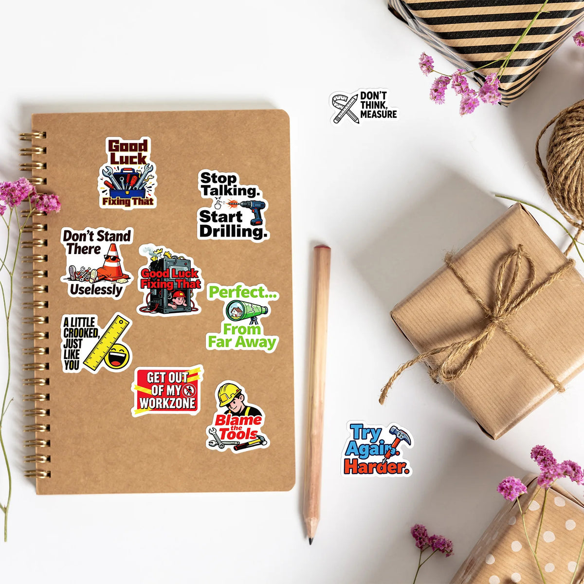A spiral notebook filled with various funny text decals and stickers related to tools and work.