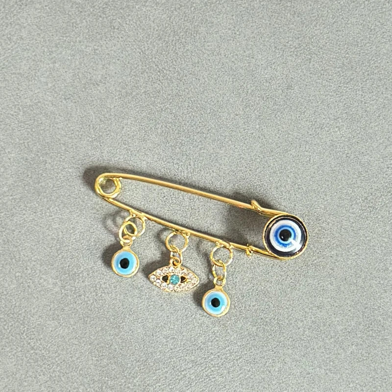 Elegant gold and silver evil eye brooch pin featuring multiple blue and black eyes.