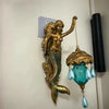 A vintage bronze resin sculpture of a mermaid with flowing hair and a teal glass lamp hanging from her tail.