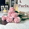 A bouquet of pink rose flower building blocks displayed next to a candle and a sign.