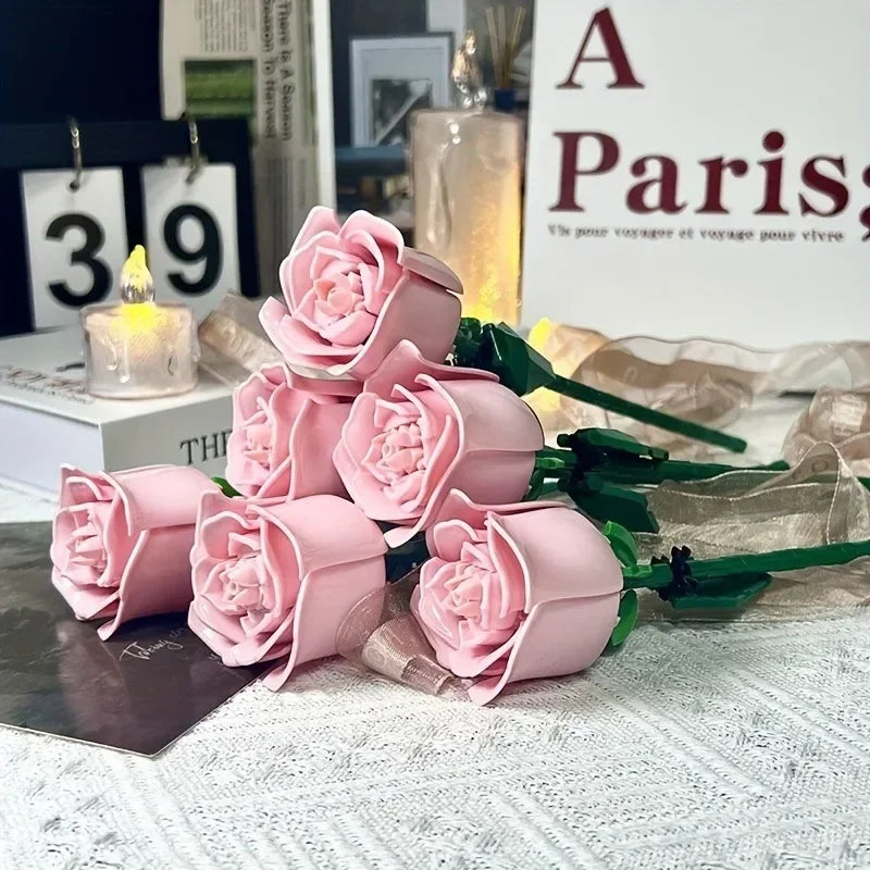 A bouquet of pink rose flower building blocks displayed next to a candle and a sign.