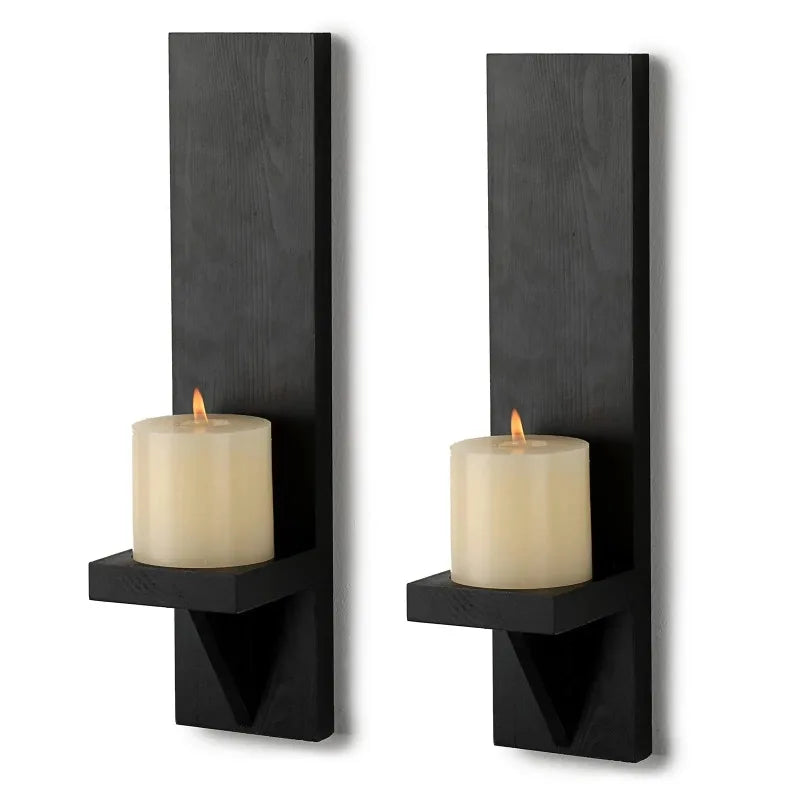 A pair of black wooden wall candle holders with cream-colored candles.