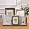 A set of three framed wooden art prints featuring the text Home is Where the Is, displayed on a wooden surface.