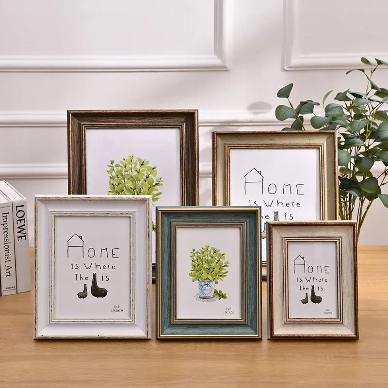 A set of three framed wooden art prints featuring the text Home is Where the Is, displayed on a wooden surface.