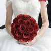 A close-up of a bouquet of deep red glitter artificial roses held by a person.