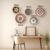 A gallery wall featuring various round boho straw and woven wall hangings of different sizes on a light beige wall.