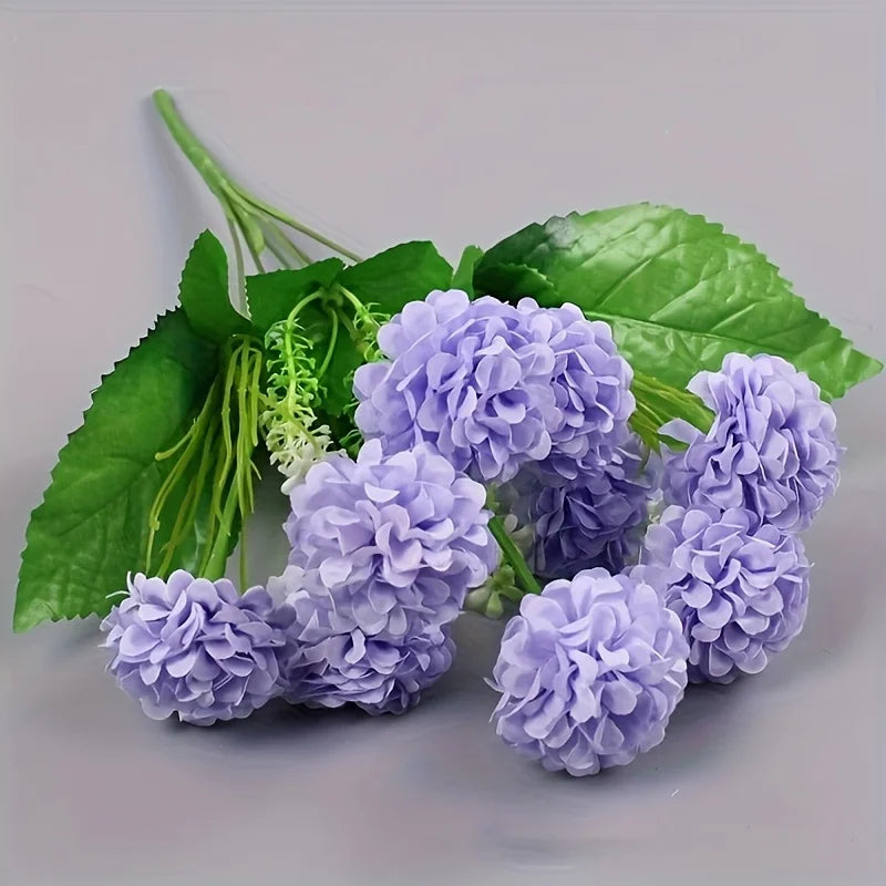 Un bouquet de fleurs d'hydrangea violette artificielle et de feuilles vertes.
