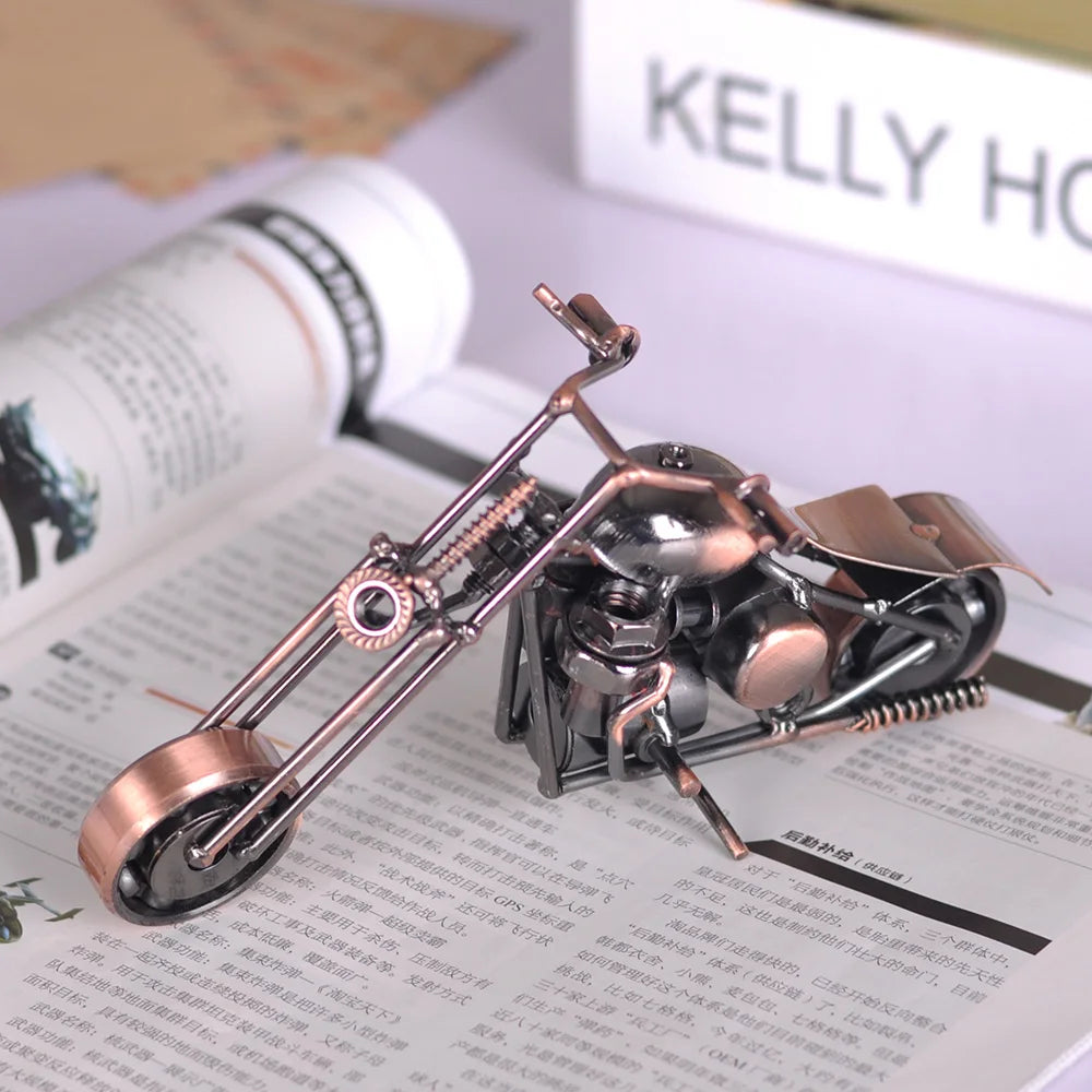 A handcrafted metal motorcycle model with a vintage appearance is displayed on a piece of paper.