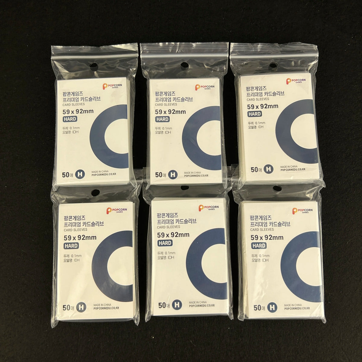 A row of ten clear protective card sleeves packaged in plastic bags with black and white labels.