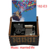 A wooden music box with a colorful balloon scene and a house, featuring a hand crank mechanism.