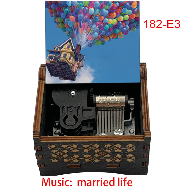 A wooden music box with a colorful balloon scene and a house, featuring a hand crank mechanism.