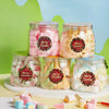 A display of glass jars filled with pink and white festive Christmas wreath stickers for gift wrapping and card decoration