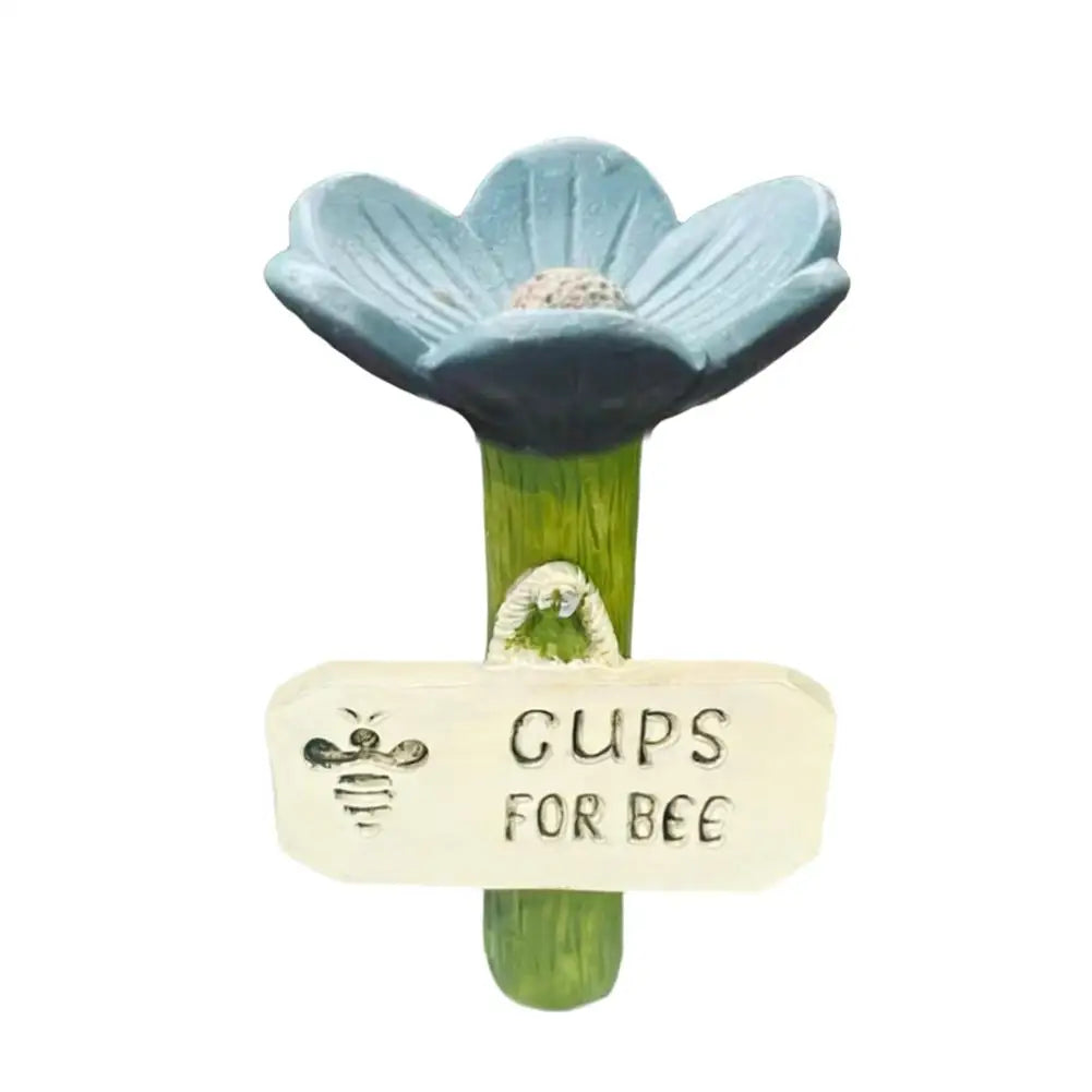 A light blue flower with a yellow center mounted on a green stick, labeled Gups for Bee.