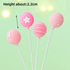 Three pink balloon cake toppers, including a star and striped spheres, are shown against a light green background.